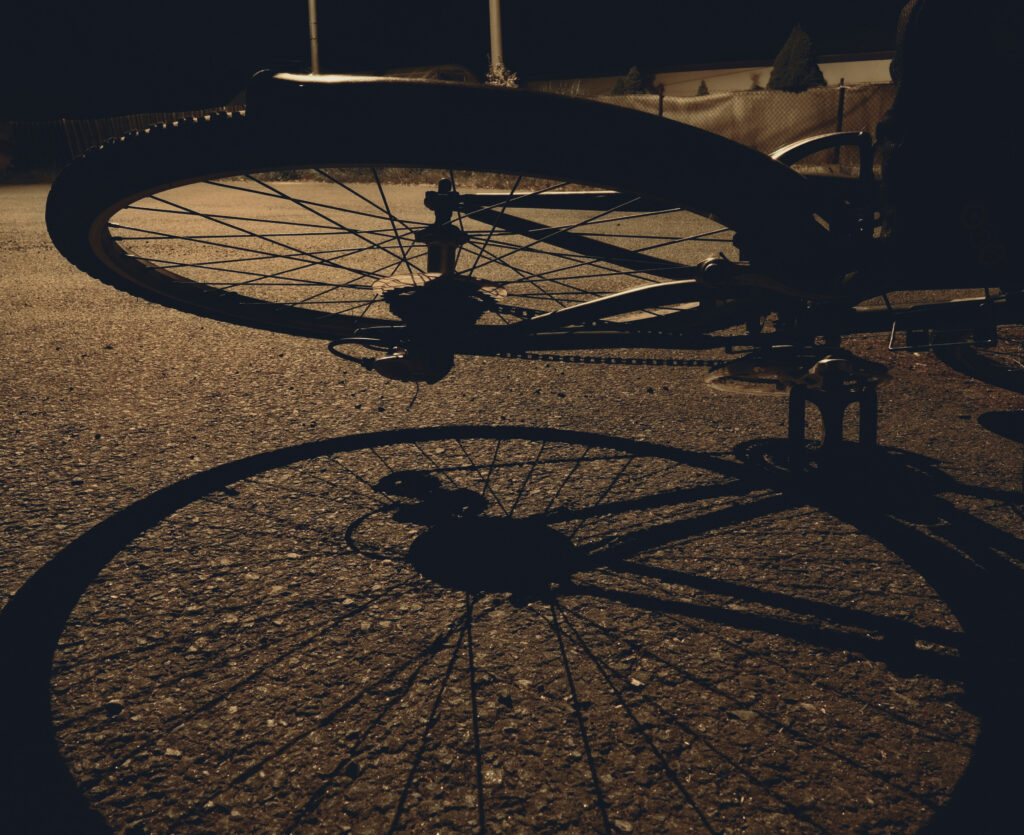 bicycle wheel and its shadow at night, to illustrate bicycle accidents caused by motor vehicle accident 